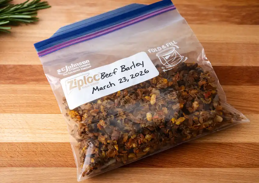 A Ziploc freezer bag filled with one portion of the dehydrated soup, sitting on a maple cutting board