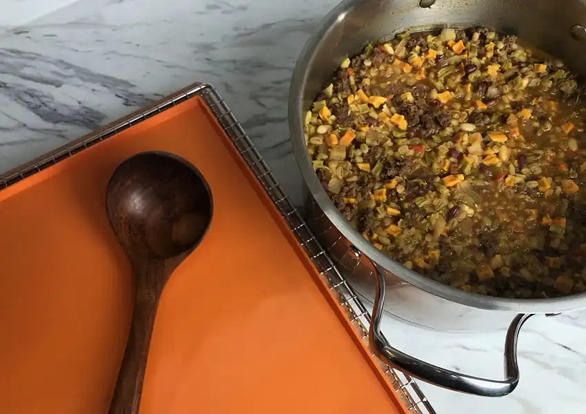 A countertop with the pot of soup ready to be spread onto dehydrator silicon mats