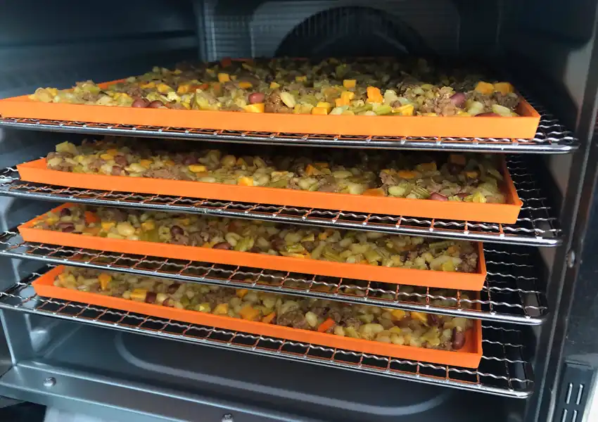 A close-up of a food dehydrator with trays of soup ready to dry