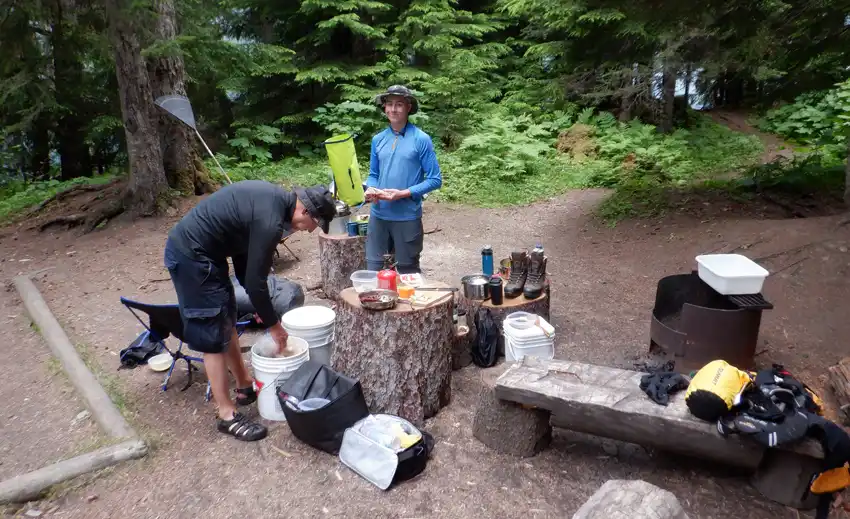 A photo of a campsite with gear and food around the area surrounded by trees