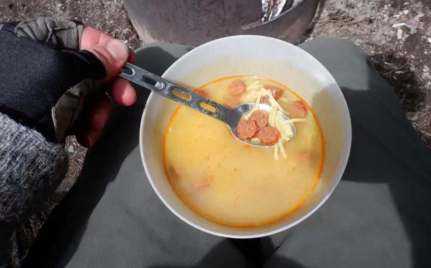 A close up of a bowl of soup with some pepperoni slices in it