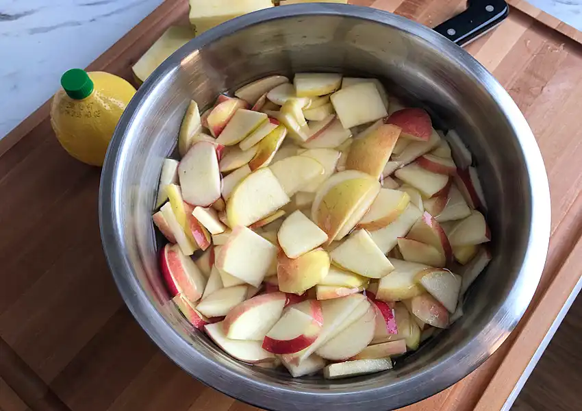 Showing sliced apples in a bowl of lemon water to prevent browning