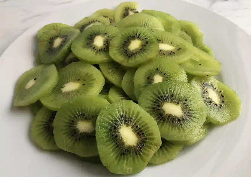 kiwi slices on a plate ready to be transferred to a dehydrator tray