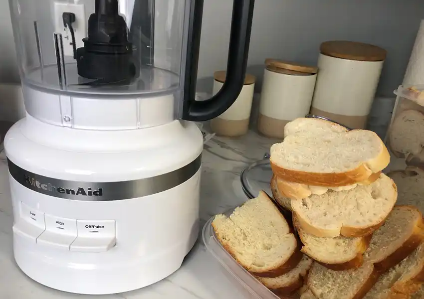 Close up photo of dried bread slices next to a food processor