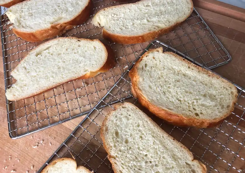 A close up of sliced French bread laid out on dehydrator racks