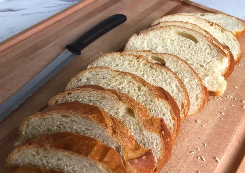 A close up photo of a sliced loaf of French bread on a cutting board