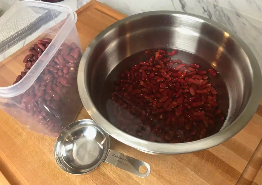 Photo showing red kidney beans soaking in a stainless steel bowl with water