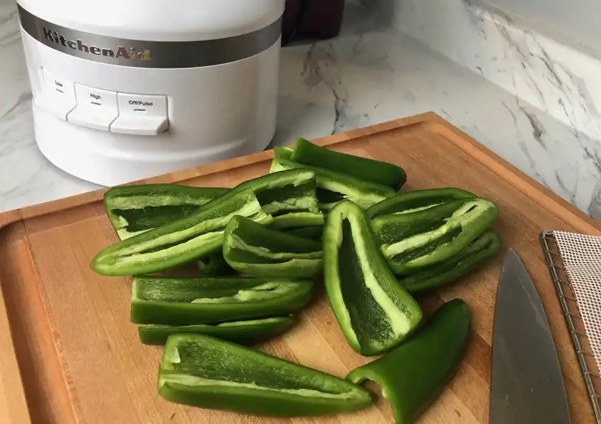 Jalapenos cut lengthwise on a maple cutting board and seeds removed