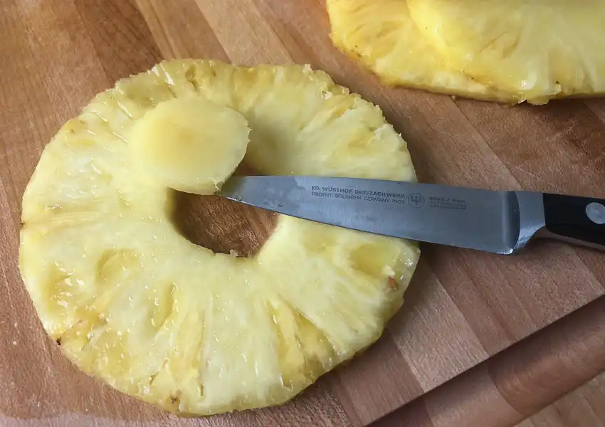 Showing how to core pineapple slices with a paring knife