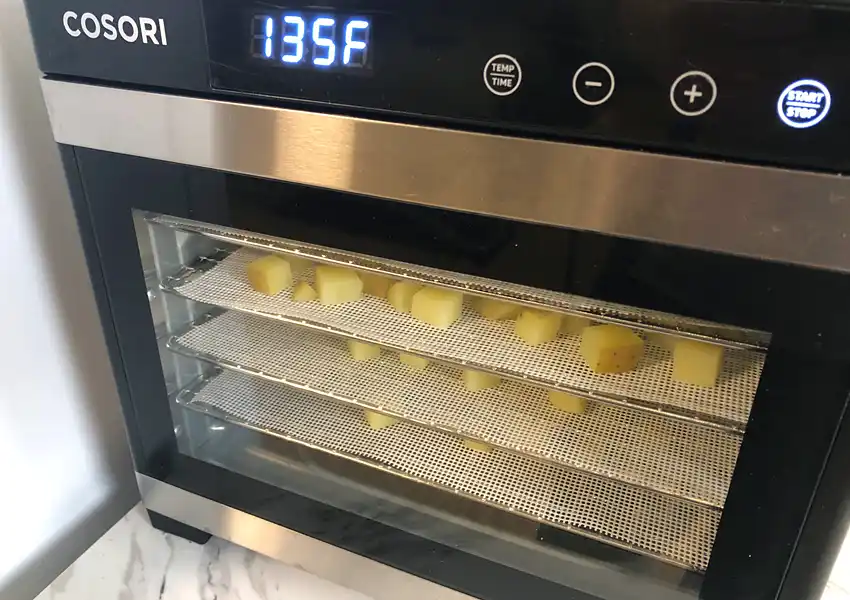 Showing the trays of diced yellow potatoes in the dehydrator