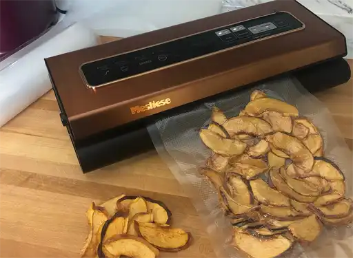 A photo of a vacuum sealer with a finished bag of dehydrated peaches on a kitchen counter